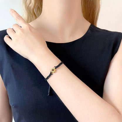 Close-up of a sunflower projection bracelet with a hidden photo inside on a black braided rope.