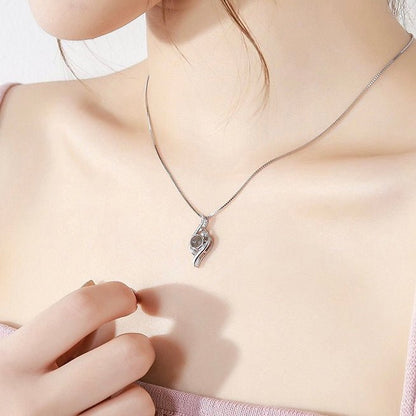 A woman wearing a leaf projection necklace with custom picture inside. 